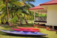 Casa de vacaciones frente al mar en Huahine, con kayaks y jardín arbolado.